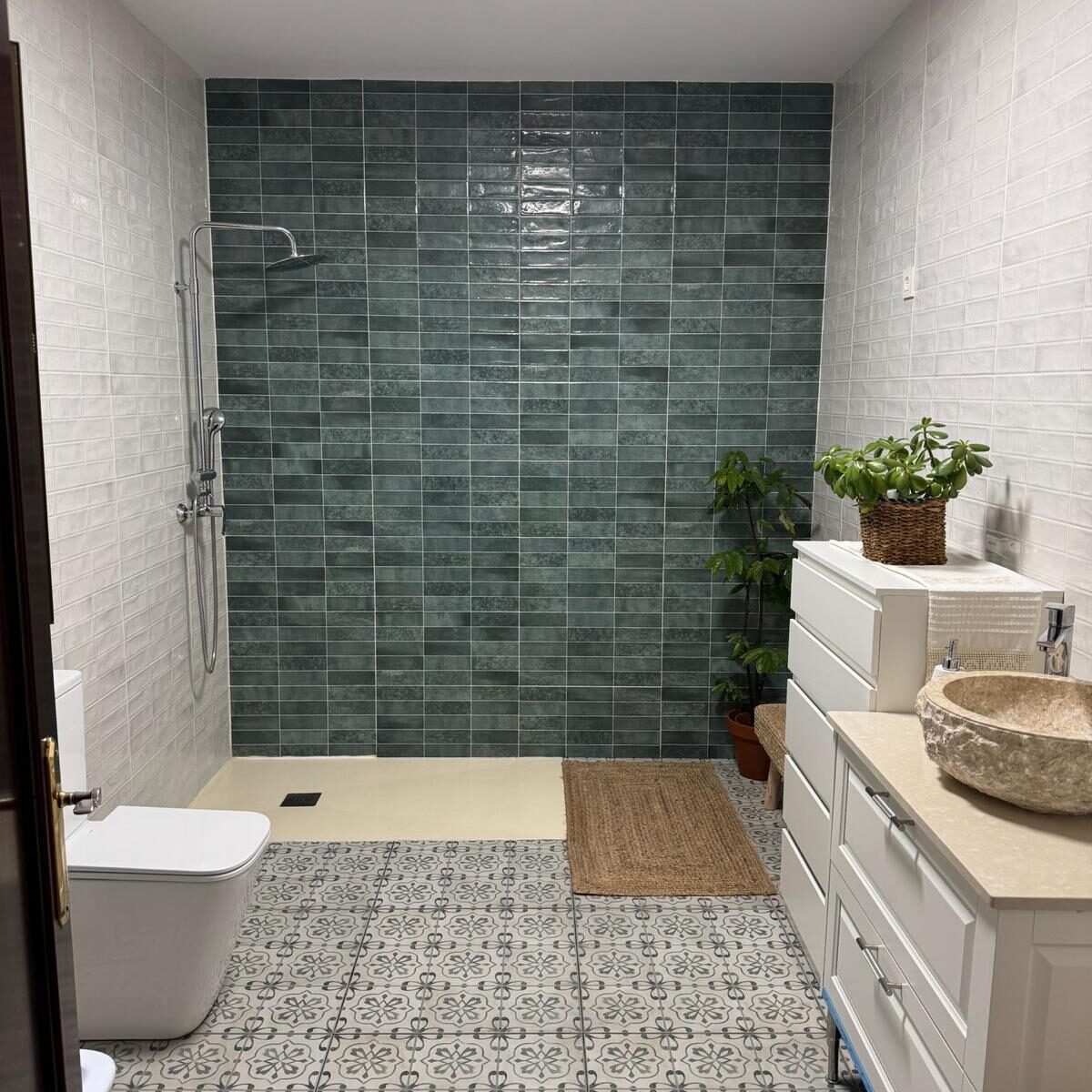Reforma integral de baño con ducha moderna en Sevilla Cuarto de baño reformado con alicatado blanco, pared en tonos verdes y plato de ducha moderno.