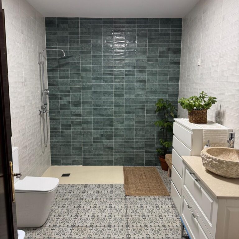 Cuarto de baño reformado con alicatado blanco, pared en tonos verdes y plato de ducha moderno.